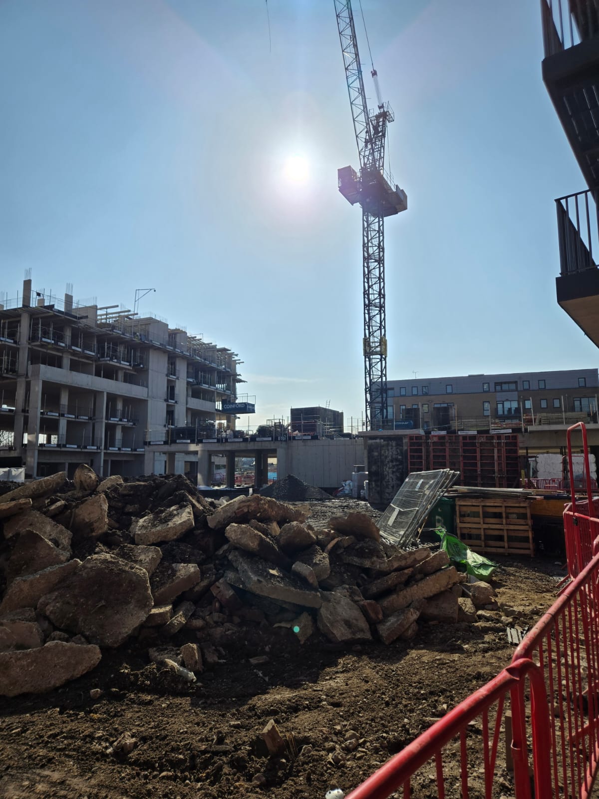 Wide site view of a large residential development with tower crane, apartment blocks, and active access routes for installation teams.